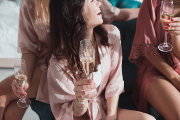 Cropped view of happy multicultural friends with champagne glasses at bachelorette party in room - 写真・画像