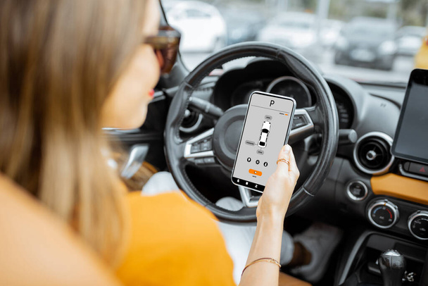 Woman controlling car with a smart phone - Foto, afbeelding