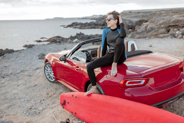 Young surfer with surfboard on the sports car on the beach - Foto, afbeelding