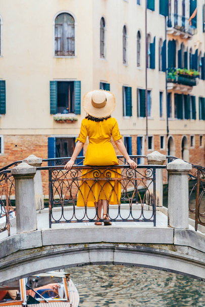 橋の上に立つ黄色のサンドレスの女性ヴェネツィア運河夏休み - 写真・画像