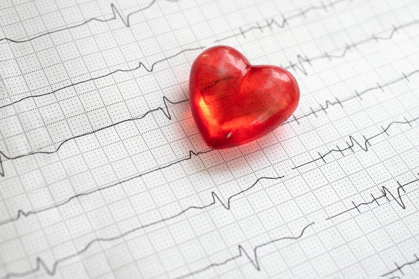 Elektrocardiogram en rood plastic hartvormig object, hartconcept, medische achtergrond - Foto, afbeelding