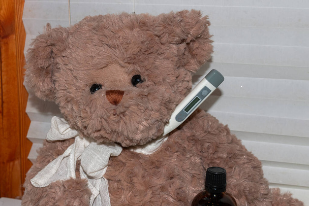 Teddy bear with face mask, clinical thermometer and medication for colds, influenza and corona virus - 写真・画像