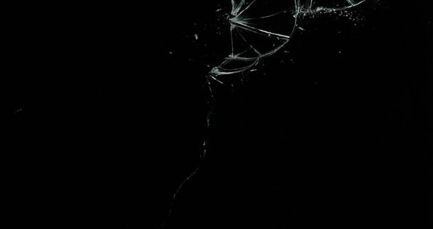 Gebroken scheuren glas breuk effect textuur geïsoleerde abstracte zwarte achtergrond. Kogel gebarsten raam met groot gat scherm spiegel wapen schot. - Foto, afbeelding