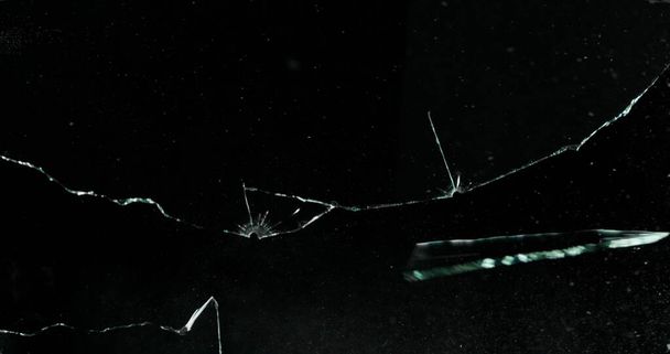Broken cracks glass fracture effect texture isolated abstract black background. Bullet cracked window with big hole screen mirror weapon shot. - Foto, afbeelding