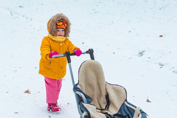 маленькая улыбающаяся девочка с санями в снежный зимний день - Фото, изображение