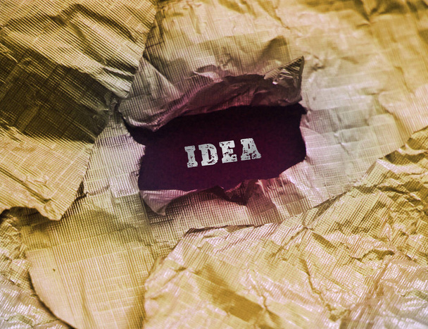 Torn golden foil paper with word Idea behind it. Business idea concept. - Photo, Image
