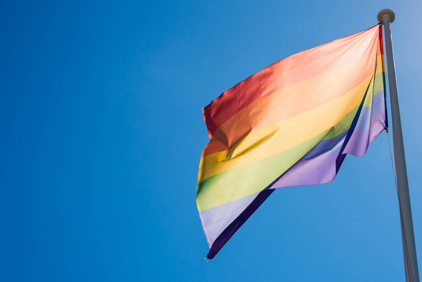 Drapeau de fierté LGBT agitant dans le ciel bleu
  - Photo, image