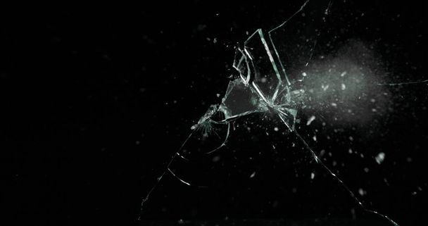 Gebrochene Risse Glasbruch Effekt Textur isoliert abstrakten schwarzen Hintergrund. Kugel zertrümmerte Fenster mit Großloch-Spiegelwaffe. - Foto, Bild