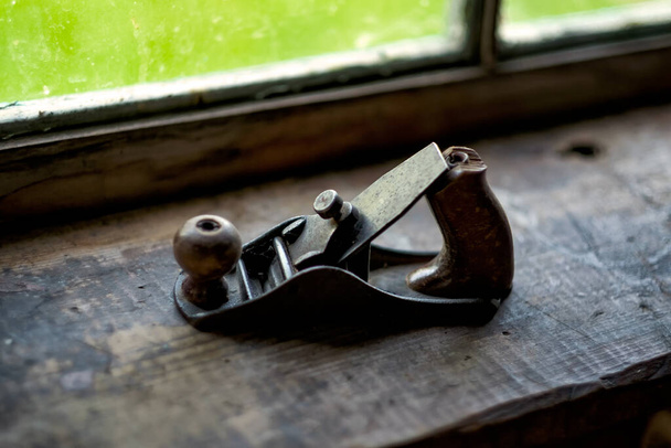 Old wooden jointer near window. Tool for carpentry work. - Photo, Image