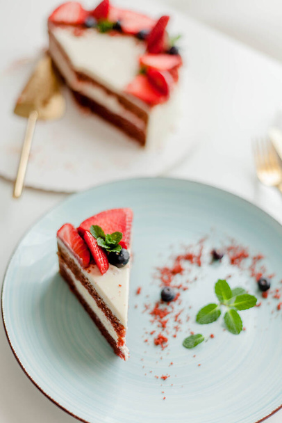 Egy szép szelet torta bogyókkal, vajkrémmel, fehér háttérrel. Vörös süteményes torta. Élelmiszer. - Fotó, kép