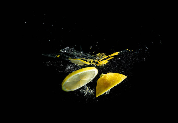 Splashing lemon in water on black background - Photo, Image