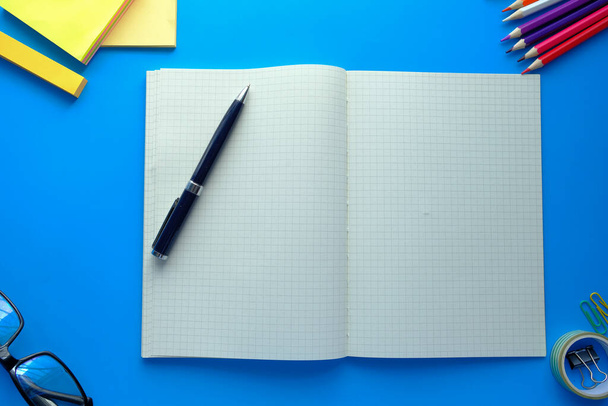 вид сверху на открытый блокнот и карандаши на синем фоне
  - Фото, изображение