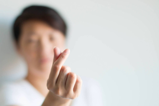 A woman making hand signs to be heart shape from the tip of thumb and index finger; meaning to tell love in Korean style called mini heart on a white background and selected focus at heart shape. - Photo, Image
