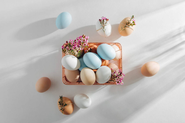 Natural Colored Eggs and flowers in basket with sunlights. Stylish Compositions in pastel colors.  Easter concept. - Zdjęcie, obraz