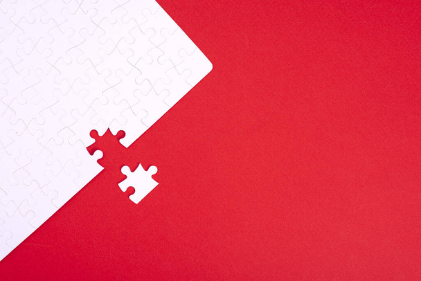A puzzle of white pieces with one seized element on a red background with place for your text - Fotó, kép