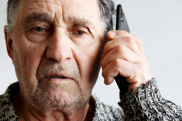 Portrait of unshaven elderly man talking on mobile phone, smartphone in male hands close up. Concept of communication in retirement - Φωτογραφία, εικόνα