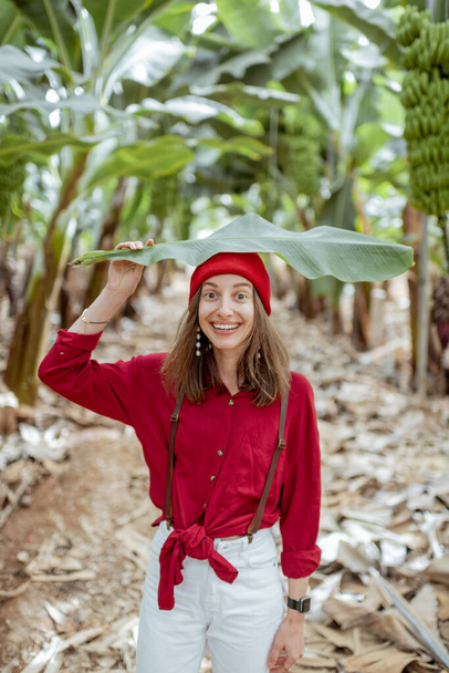Hermosa mujer con hoja de plátano en la plantación
 - Foto, imagen