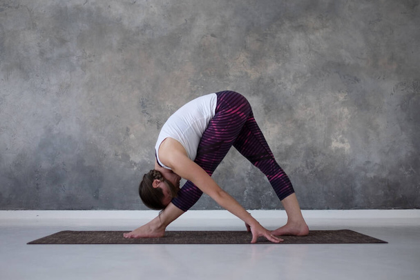woman practicing yoga, standing in Parsvottanasana pose on mat, Pyramid exercise - Foto, afbeelding