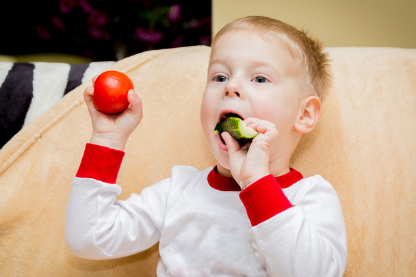Il bambino mangia un pomodoro e un cetriolo
 - Foto, immagini