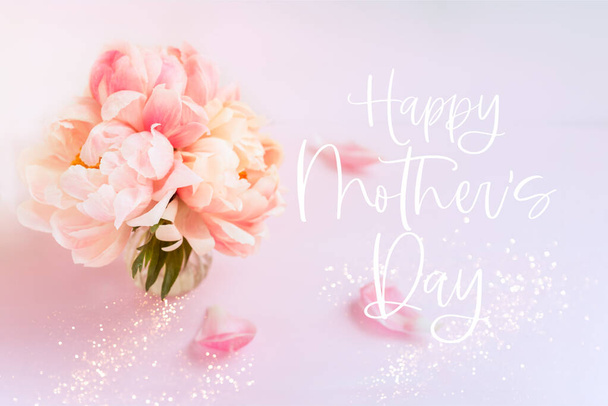 Happy Mother's Day phrase. Fresh bunch of pink peonies and roses in a vase on pink background. Card concept, pastel colors, copy space - Photo, Image