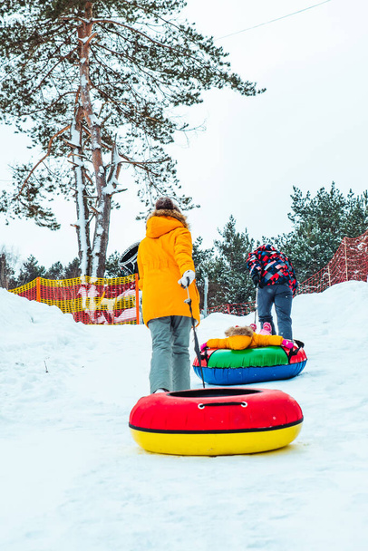 people climbing up by hill for snow tubing. winter leisure activities - Photo, Image
