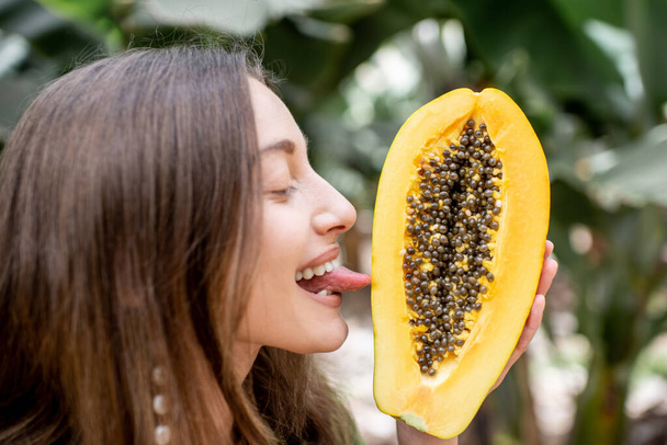 Portrait of a woman licking papaya fruit - Foto, afbeelding