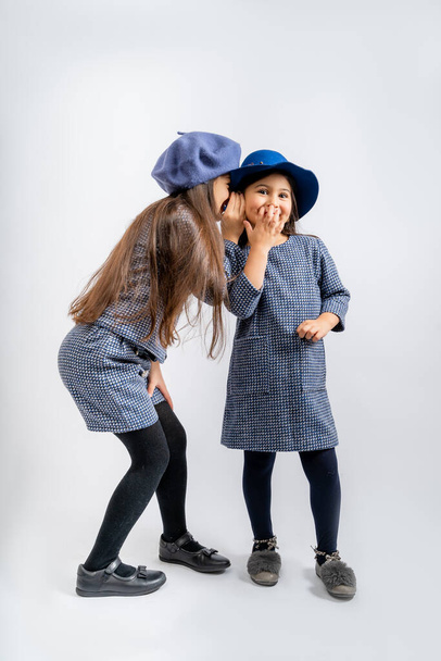 Children in a blue jacket with white and black spots, a blue cap, blue shorts with the same spots, black tights, black shoes, a blue dress with blue tights, gray shoes isolated on a white background. - Photo, Image