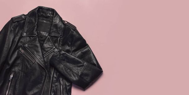ピンクの背景のトップビューに黒の女性の革のジャケット。ファッショナブルな現代の流行の女性の服。ヴィンテージバイカージャケット。ブラック本革 - 写真・画像