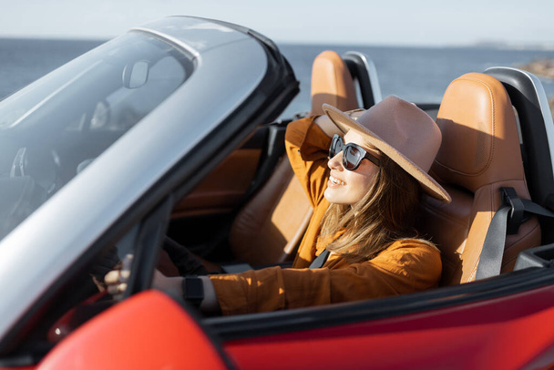 海の近くでキャブリオレットを運転する女性 - 写真・画像