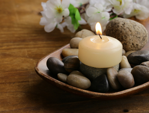 Still life a lit candle and stones on wooden background - Photo, Image