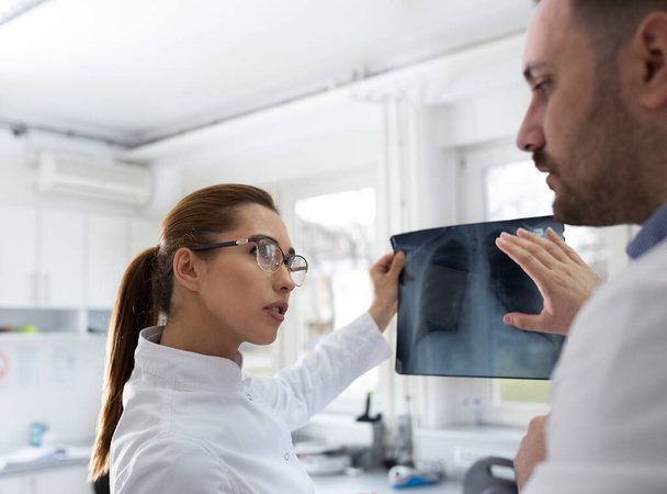 Dva lékaři muži a ženy se dívají na rentgen v laboratoři - Fotografie, Obrázek