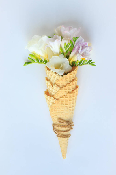 a bouquet of delicate flowers in a waffle Cup for ice cream on a white background, top view, summer and spring minimalism - 写真・画像