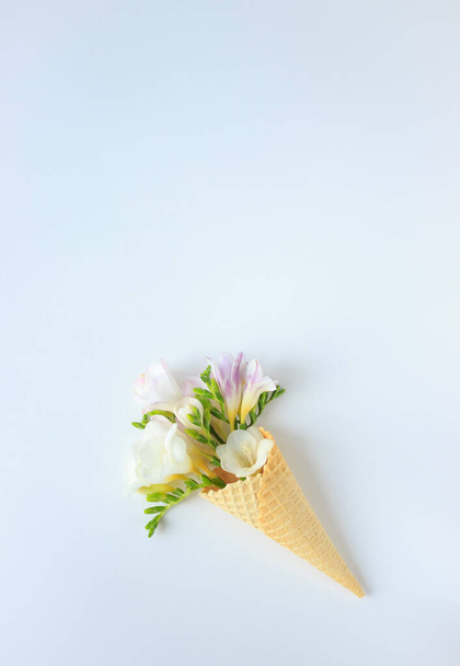 a bouquet of delicate flowers in a waffle Cup for ice cream on a white background, top view, summer and spring minimalism - Zdjęcie, obraz