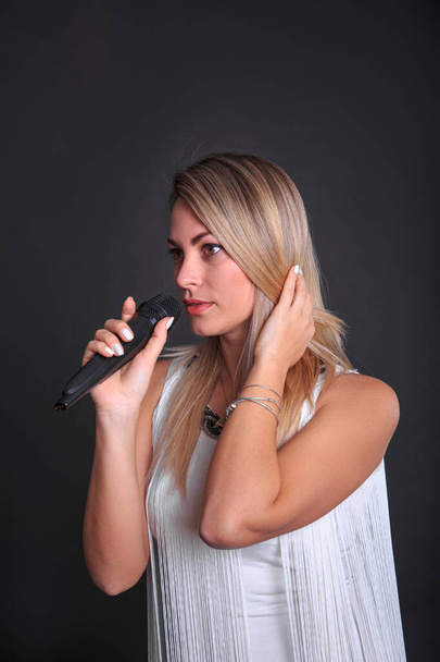 Portrait of a girl with a microphone in a photo studio on a black background - Fotoğraf, Görsel