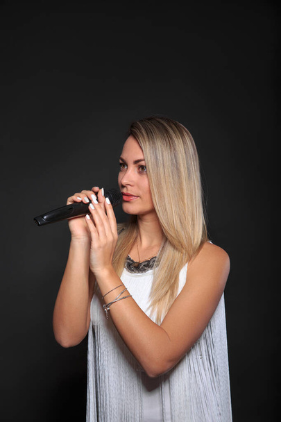 Portrait of a girl with a microphone in a photo studio on a black background - Fotoğraf, Görsel