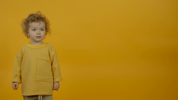 Imádnivaló göndör gyermek tánc sárga háttér - Felvétel, videó
