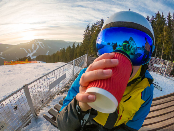 mujer bebiendo té en la cima de la montaña nevada. reflexión en máscara de esquí. estilo de vida deporte de invierno. atardecer paisaje
 - Foto, imagen