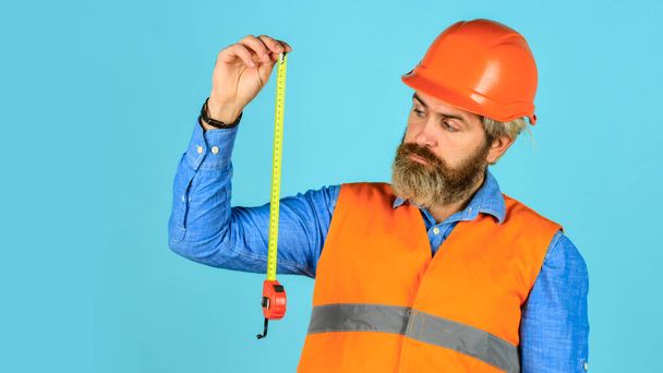 measurement. brutal hipster worker use tape measure. Man in uniform works on the production. Industrial modern technology. builder with tape. Yellow colored measuring tape. bearded man in hardhat - Foto, immagini
