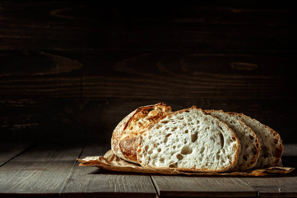Bread, traditional sourdough bread cut into slices on a rustic wooden background. Concept of traditional leavened bread baking methods. Healthy food. - Photo, Image