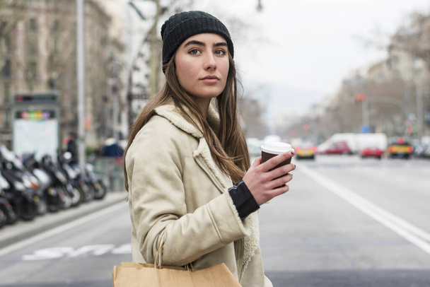 Portrait of an european woman walking in a city street, with takeaway coffee in hands - Photo, Image