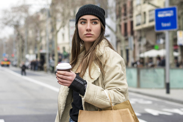 Retrato de una mujer europea caminando por una calle de la ciudad, con café para llevar en las manos
 - Foto, imagen