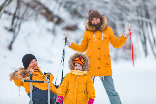 jong gezin samen buiten op besneeuwde winterdag geel jassen familie looks - Foto, afbeelding