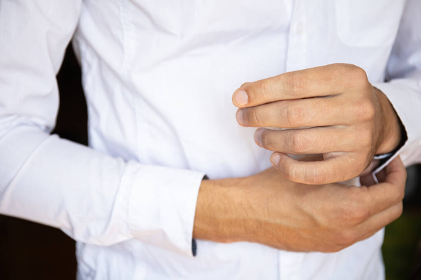 man fastens buttons on sleeves white shirt - Foto, immagini