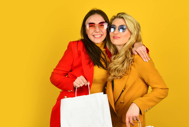 two female carry shopping bags. big sales and black friday. bright autumn colors. autumn and spring fashion style. trendy look for any season. friendship and sisterhood. couple of women go shopping - Фото, зображення