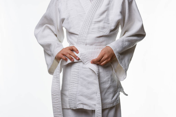 Stages of correct tying of the belt by a teenager on a sports kimono, step five - Foto, afbeelding