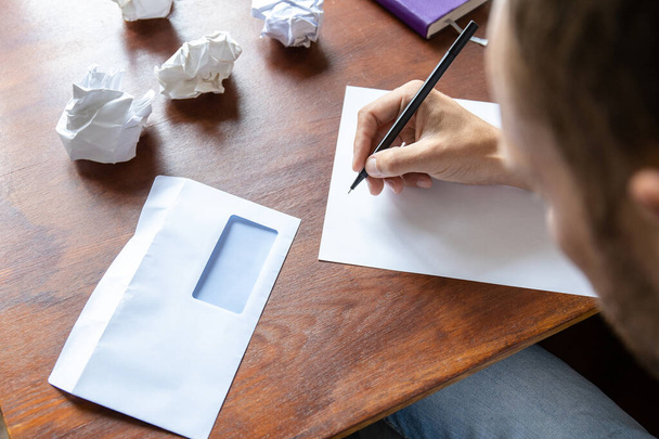 a man writes a letter on a sheet by hand - Φωτογραφία, εικόνα