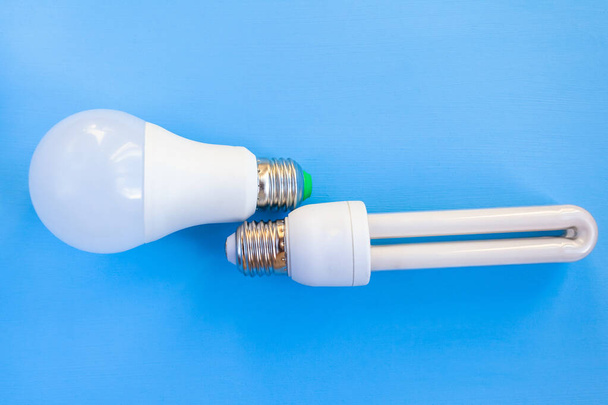 LED and energy-saving light bulbs lie side by side on a blue background - Zdjęcie, obraz