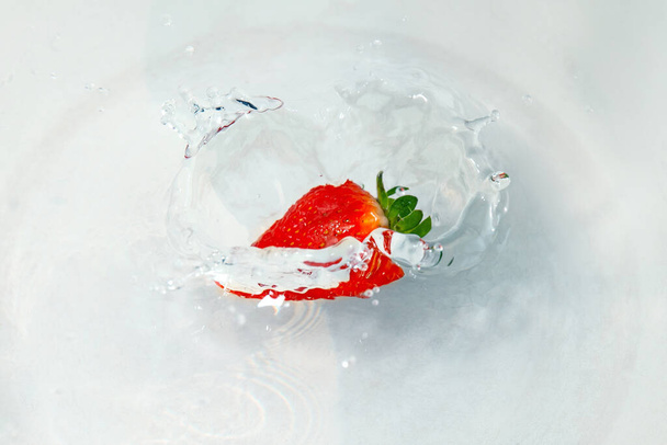 bright red juicy strawberries falling into the water with splashes - Foto, afbeelding