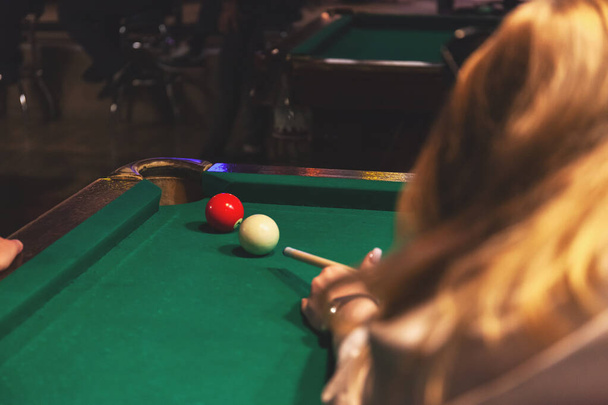 hand of a girl playing billiards, trying to hit the ball, retro toned - Fotó, kép