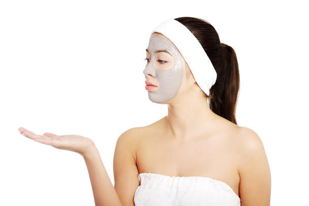 Красивая женщина в полотенце с маской для лица и повязкой на голове
. - Фото, изображение